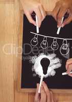 Hands drawing light bulbs on blackboard
