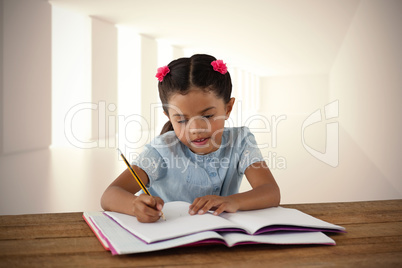 Composite image of girl writing in book at desk