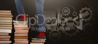 Composite image of low section of boy climbing stack of books