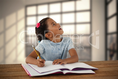 Composite image of girl looking up while writing in book