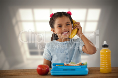 Composite image of smiling girl using banana as phone