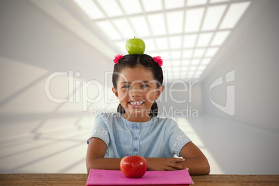 Composite image of smiling girl with granny smith apple on head
