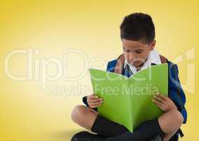 Schoolboy reading in front of yellow background