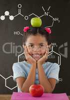 Happy student girl at table against grey blackboard with school and education graphic