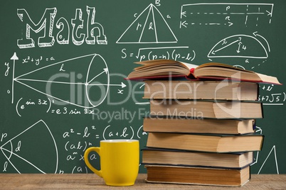Books on the table against green blackboard with education and school graphics
