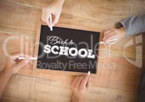 Hands writing Back to school on blackboard
