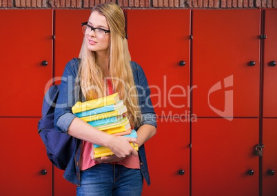male student holding books in front of lockers