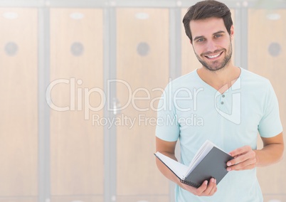 male student holding book in front of lockers