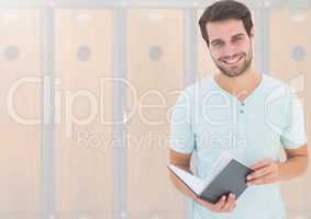 male student holding book in front of lockers