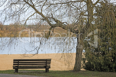 Late autumn on the river: an empty beach and a bench.