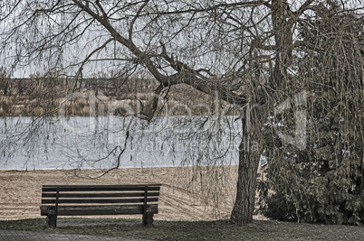 Late autumn on the river: an empty beach and a bench.