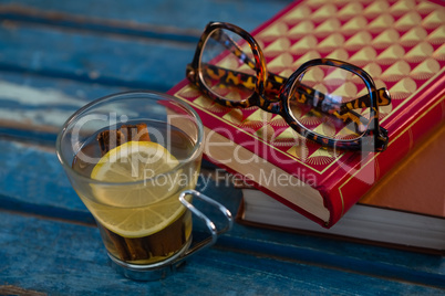 Close up of lemon tea by books and eyeglasses