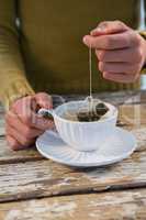 Mid section of woman dipping tea bag in cup