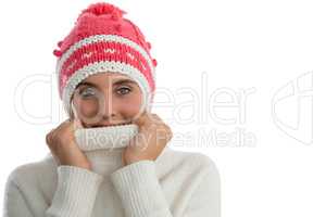 Portrait of woman wearing knit hat while covering face with turtleneck sweater