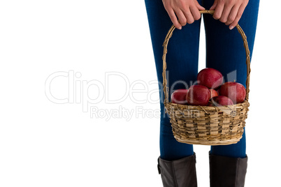 Mid section of woman holding apples in wicker basket