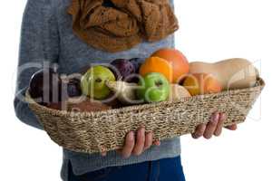 Mid section of woman carrying vegetables and fruits in wicker basket