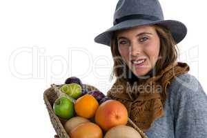 Portrait of smiling woman carrying fruits and vegetables in basket