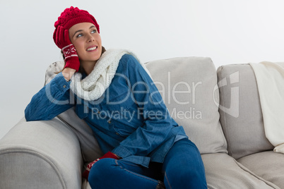 Thoughtful woman looking away while sitting on sofa Thoughtful woman looking away while sitting on sofa