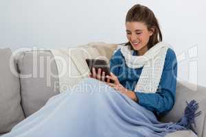 Smiling woman using tablet computer while sitting on sofa