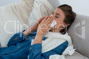 Young woman rubbing nose while lying on sofa