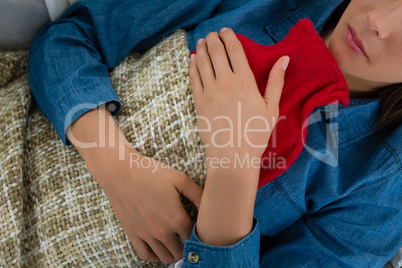 Mid section of woman with hot water bottle while sleeping