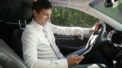 Smiling bussinessman in car texting on smartphone