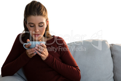 Woman having coffee while sitting on sofa