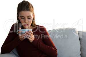 Woman having coffee while sitting on sofa