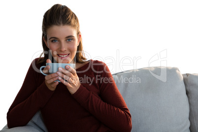 Portrait of woman having coffee while sitting on sofa