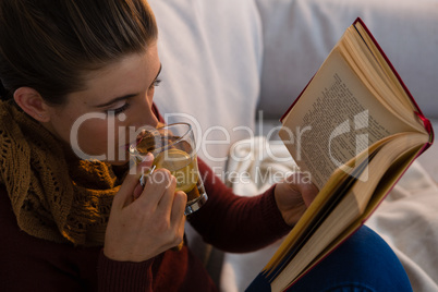 High angle view of woman having tea while reading book