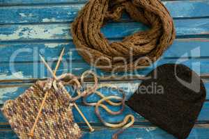 High angle view of muffler with knit hat and knitting needles