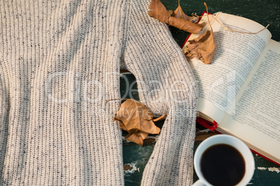 High angle view of sweater by open book and coffee cup