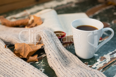 Close up of sweater by open book and coffee cup