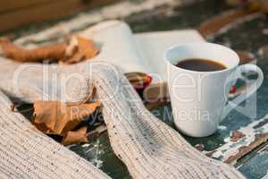 Close up of sweater by open book and coffee cup