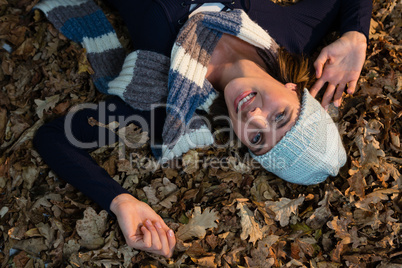 Overhead view of happy woman lying on dry leaves