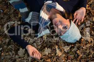 Overhead view of happy woman lying on dry leaves