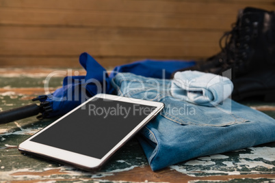 Close up of tablet computer with jeans and gloves by umbrella