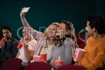 Friends taking a selfie while watching movie