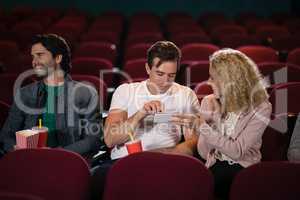 Friends using mobile phone while watching movie