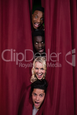 Actors hiding behind stage curtains