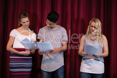 Actors reading their scripts on stage