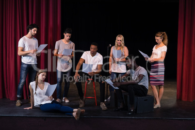 Actors reading their scripts on stage
