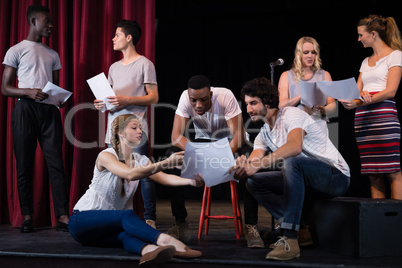 Actors reading their scripts on stage