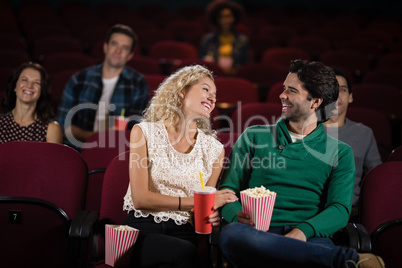 Couple smiling while watching movie in theatre