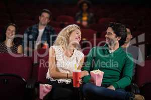 Couple smiling while watching movie in theatre