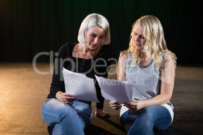 Actors reading their scripts on stage