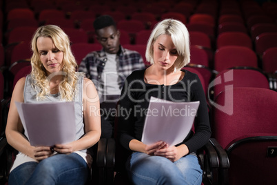 Actors reading their scripts on stage in theatre