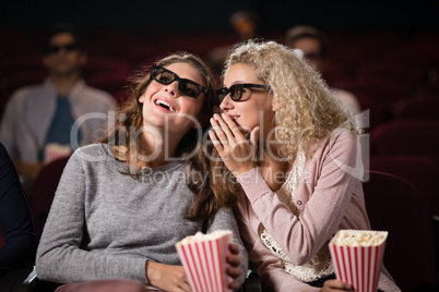 Female friends gossiping while watching movie