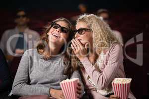 Female friends gossiping while watching movie