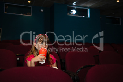 Girl having drink on seat in movie theater
